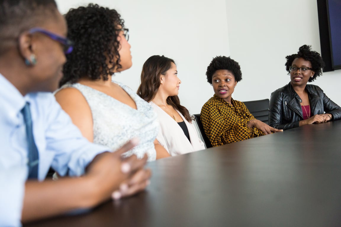 Four Women and One Man Sitting Near Table Inside Room